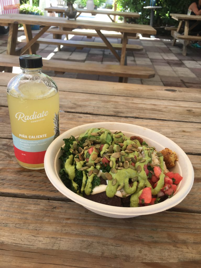 Close up shot of the Dale bowl at della bowls, with a glass bottle of yellow kombucha next to it. 