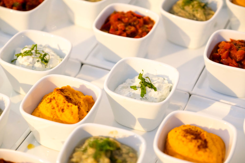 Mezze. Variety of colors of dips and spreads in little bowls, ready for service. 
