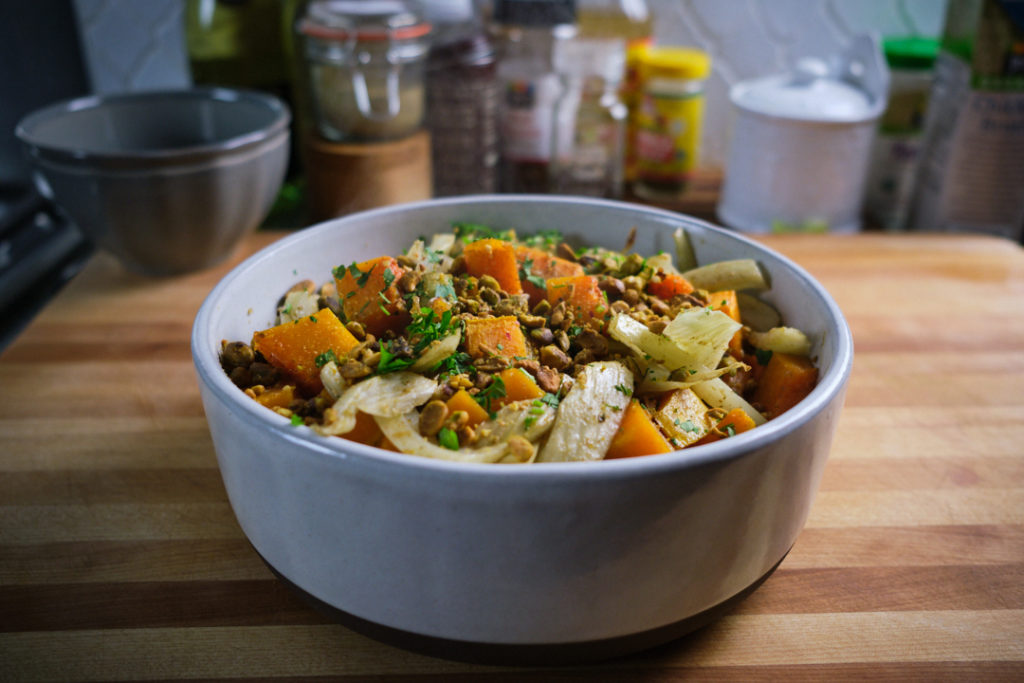 A white bowl filled with a recipe variation for roasted butternut squash. The bowl is filled with roasted butternut squash, fennel, nuts and spiced with za'atar. 