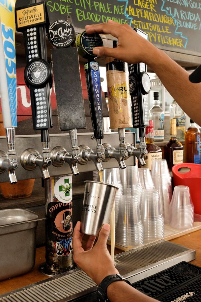 Local craft beers being poured into  reusable clean canteen cups. 