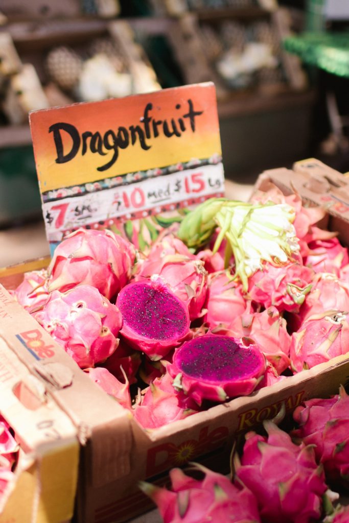 dragonfruits at a farmers market in a bon with a sign