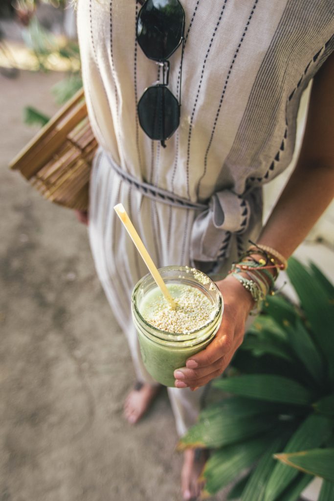 Woman holding green juice in a mason jar with a sustainable straw
