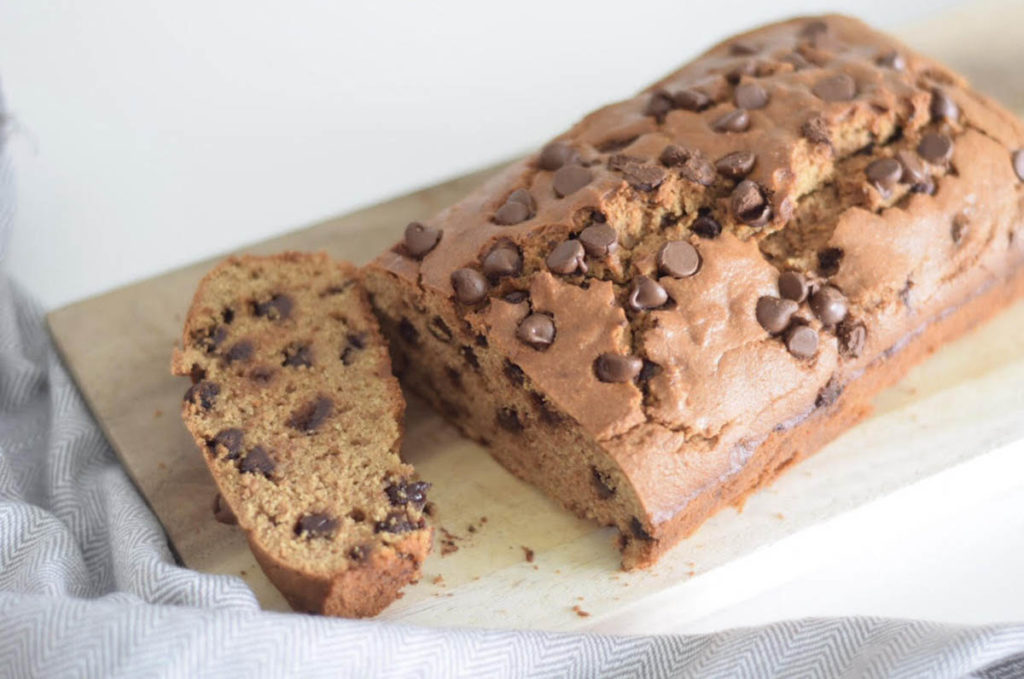 A loaf of chocolate bread on a wooden cutting board shows the finished product of this delicious recipe.